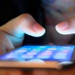 Держит в руках смартфон